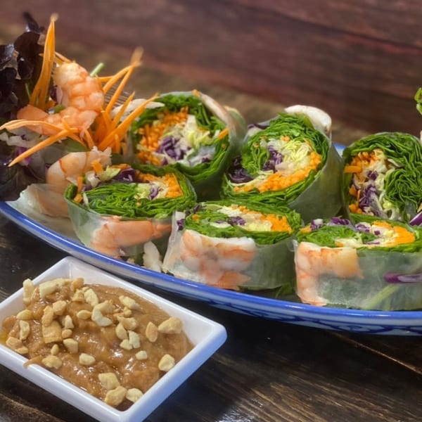 Fresh Thai spring rolls with shrimp, lettuce, carrots, and cabbage, served with peanut sauce.